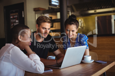 Friends using laptop while having coffee