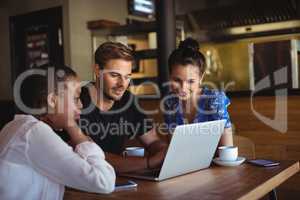 Friends using laptop while having coffee