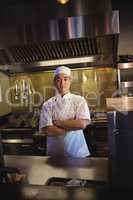 Smiling chef standing with arms crossed in the commercial kitchen