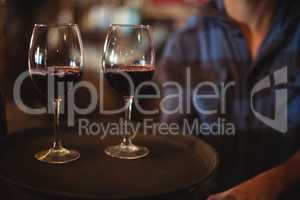 Bar tender holding a tray with glasses of red wine