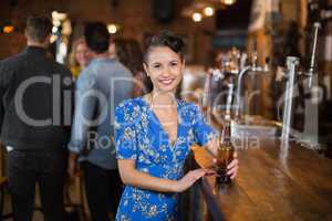 Portrait of smiling woman holding beer bottle in pub