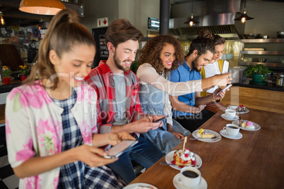 Smiling friends using their mobile phones in restaurant
