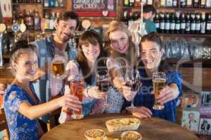 Portrait of happy friends holding drinks in bar