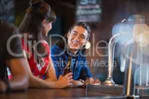 Happy friends looking at each other while leaning on bar counter