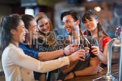 Cheerful friends toasting beer bottles