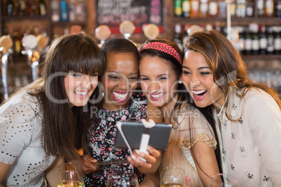 Cheerful female friends taking selfie in pub