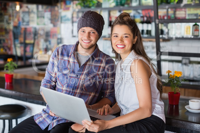 Portrait of friends using laptop in restaurant