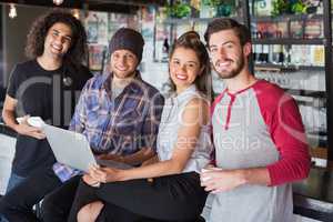 Smiling friends using laptop in restaurant