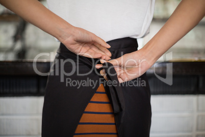 Close up of waitress tying apron