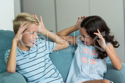 Boy and girl sitting on sofa teasing each other in living room