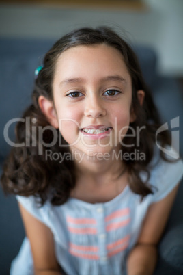 Portrait of smiling girl sitting on sofa in living room