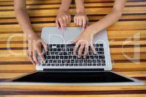 Hand of siblings using laptop in kitchen