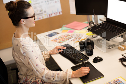 Businesswoman using computer while working on digitizer at office