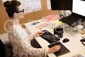 Businesswoman using computer while working on digitizer at office