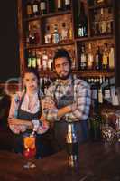 Portrait of waiter and waitress standing with arms crossed at counter