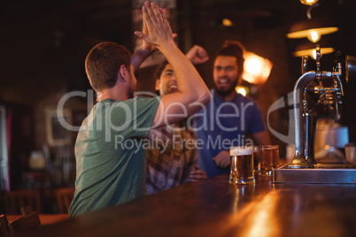 Group of male friends giving high five to each other