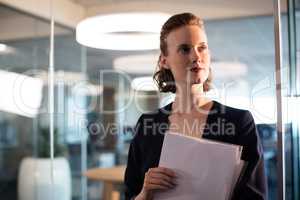 Businesswoman holdings documents while looking away