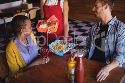 Waitress serving burger and french fries to customer