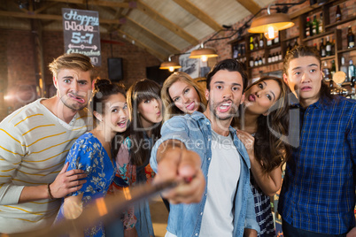 Cheerful friends taking selfie in pub