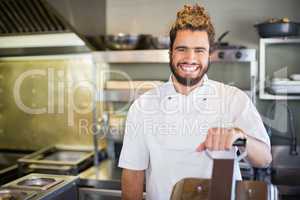 Smiling male chef standing in commercial kitchen