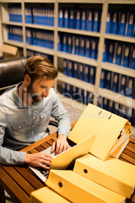 Businessman using laptop on table in file storage room