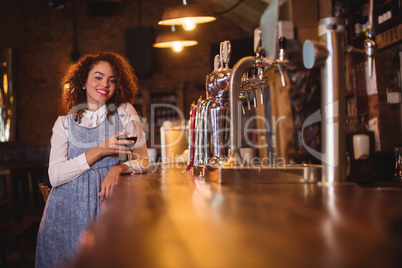 Portrait of young woman having wine at counter