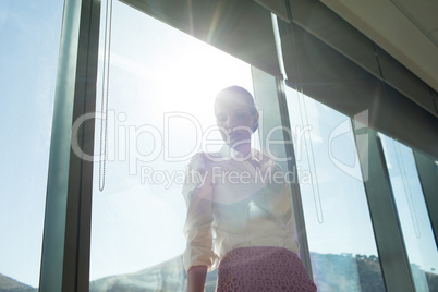 Businesswoman standing by brightly lit window in office