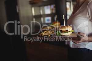 Woman carrying burger and french fries in a tray at restaurant