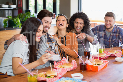 Woman showing mobile to cheerful friends in restaurant