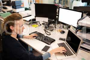 Businesswoman typing on laptop while using desktop pc