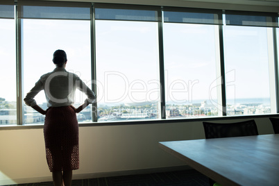 Female business executive looking through window in conference room