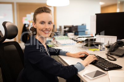 Portrait of businesswoman typing on keyboard at office