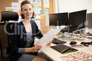 Portrait of businesswoman holding document at desk