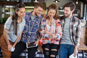 Friends laughing while watching mobile phone in restaurant