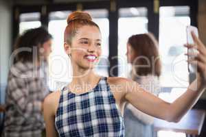 Smiling woman taking selfie in restaurant