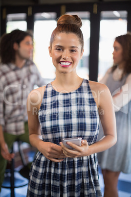 Portrait of smiling woman holding mobile phone in restaurant