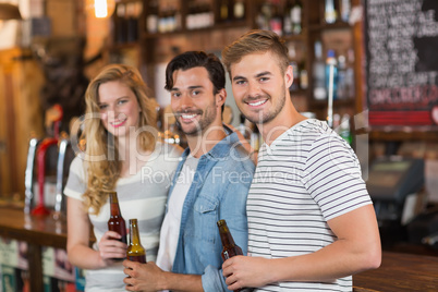 Happy friends holding beer bottles at pub