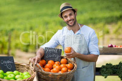 Portrait of smiling man standing by fresh fruits in wicker basket
