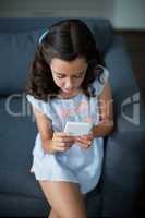Girl sitting on sofa and using mobile phone in living room