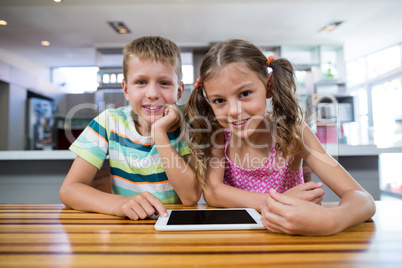 Happy sibling with digital tablet in kitchen
