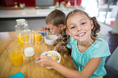 Smiling sibling having breakfast cereal in kitchen