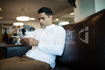 Young businessman using mobile phone while sitting at office