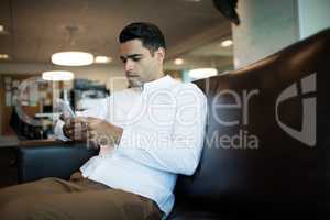 Young businessman using mobile phone while sitting at office