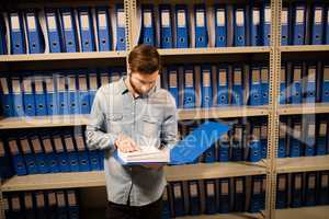 High angle view of businessman reading file in storage room