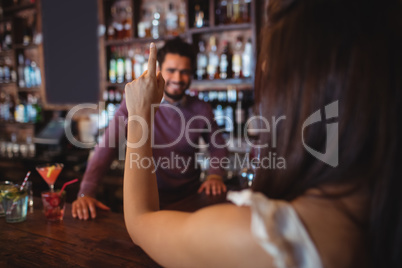 Woman asking for a drink to bar tender