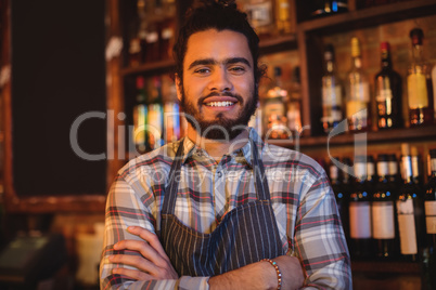 Portrait of smiling waiter standing with arms crossed