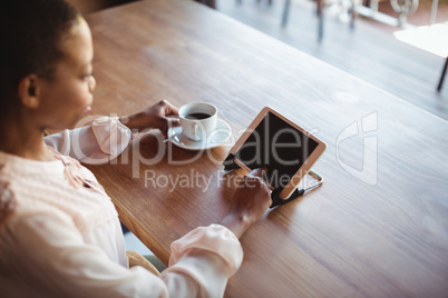 Woman using digital tablet while having coffee