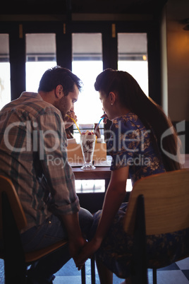Couple holding hands while having milkshake