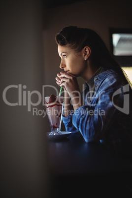 Thoughtful woman having milkshake