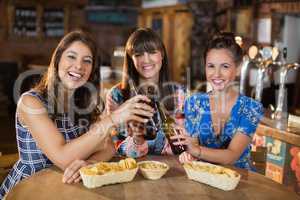 Female friends toasting beer bottles in bar